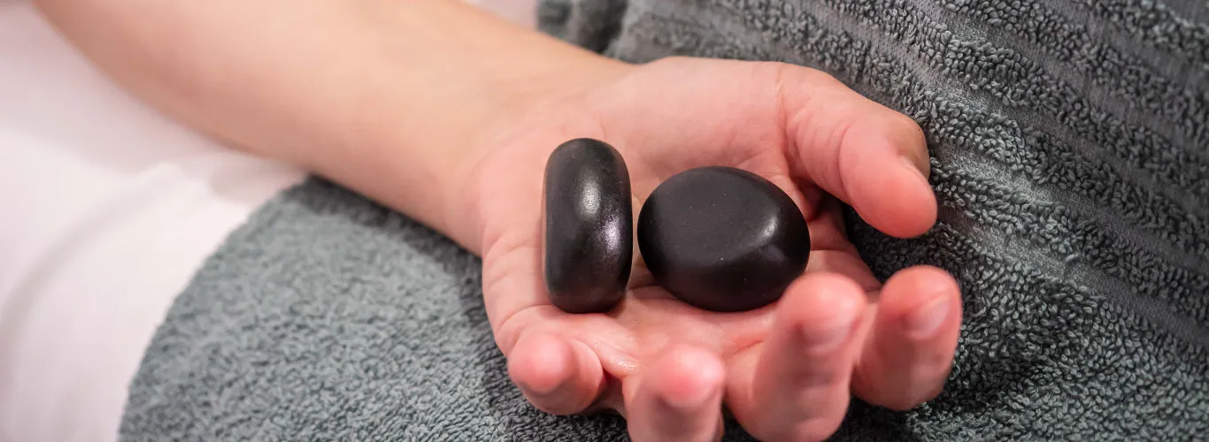 Mano con piedras calientes de masaje, banner apaisado